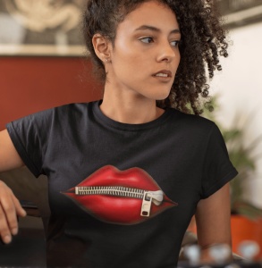 Fată purtând un tricou negru cu un design grafic ce afișează buze roșii cu un fermoar închis, într-un cadru interior modern.