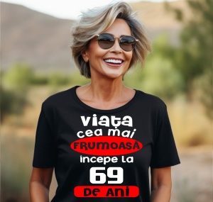 Femeie care poartă un tricou negru personalizat cu mesajul: ''Viata cea mai frumoasa incepe la 69 de ani''.