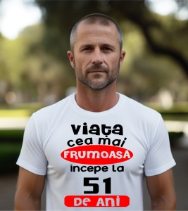 Un bărbat purtând un tricou alb cu textul ''Viața cea mai frumoasă începe la 51 de ani''.