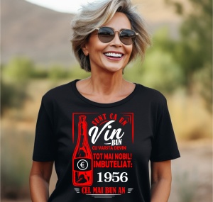 Femeie zâmbitoare purtând un tricou negru cu un mesaj în română despre vin, în care se menționează că este ca un vin bun care devine mai nobil cu vârsta, îmbuteliat în 1956, cel mai bun an.