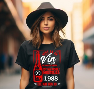Femeie zâmbitoare purtând un tricou negru cu un mesaj în română despre vin, în care se menționează că este ca un vin bun care devine mai nobil cu vârsta, îmbuteliat în 1988, cel mai bun an.