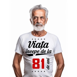 Bărbat în vârstă cu barbă albă, purtând un tricou alb cu mesajul 'Viața începe de la 81 de ani', pe un fundal alb simplu.