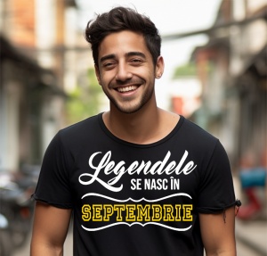 Un tânăr zâmbitor, cu părul aranjat, purtând un tricou negru cu mesajul: „Legendele se nasc în Septembrie”. Bărbatul se află pe o stradă urbană, cu clădiri și oameni în fundal.