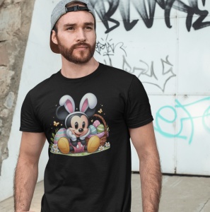 Bărbat purtând un tricou negru cu un design festiv de Paște care îl înfățișează pe Mickey Mouse purtând urechi de iepuraș, așezat lângă un coș cu ouă colorate. Fundalul include un perete cu graffiti.