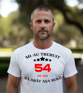 Un bărbat purtând un tricou alb cu mesajul: „Mi-au trebuit 54 de ani să arăt așa bine”