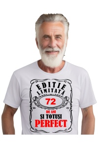 Un bărbat purtând un tricou alb cu mesajul: „Ediție limitată, 72 de ani și totuși perfect”. Bărbatul afișează o atitudine veselă și pozitivă.