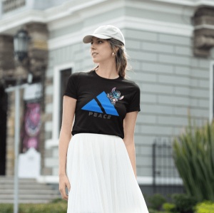 Femeie purtând un tricou negru cu un design al unui triunghi albastru și un personaj animat albastru(Stitch), care iese parțial din spatele triunghiului. Sub design apare textul 'PEACE'. Femeia poartă și o șapcă deschisă la culoare și o fustă albă, într-u