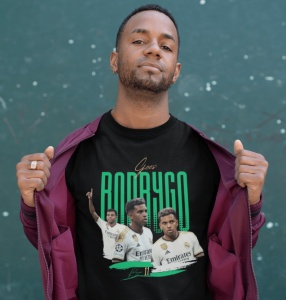 Un bărbat poartă un tricou negru cu design grafic dedicat jucătorului de fotbal Rodrygo, incluzând imagini cu acesta în diferite ipostaze și numele său scris cu litere verzi.