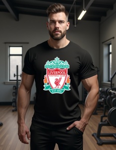 Bărbat purtând un tricou negru cu sigla echipei de fotbal Liverpool FC, având designul tradițional roșu și verde cu pasărea Liver și sloganul 'You’ll Never Walk Alone' în partea superioară a emblemei. Bărbatul se află într-o sală de sport, iar fundalul in