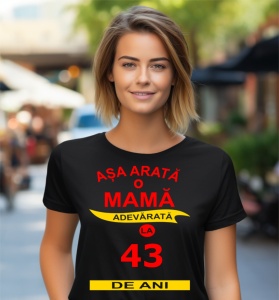 Femeie zâmbitoare purtând un tricou cu mesajul: ''Așa arată o mamă adevărată la 43 de ani''