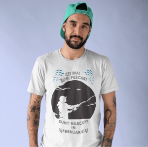 Imagine cu un bărbat purtând un tricou alb pe care este imprimat un design cu mesajul 'Cei mai buni pescari sunt născuți în februarie', cu o siluetă de pescar și ilustrații de pești.