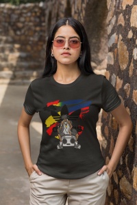 Femeie purtând un tricou negru cu un design colorat inspirat de cultura hip-hop, ce prezintă un personaj desenat cu o bandană, ochelari de soare și un radio boombox, stând în fața unui fundal abstract cu linii colorate, pozând într-un cadru urban.