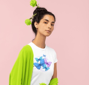 Fată purtând un tricou alb cu un design grafic de fluturi albastri și mov, cu un șal verde pe umeri și trandafiri verzi în păr, pe un fundal roz.