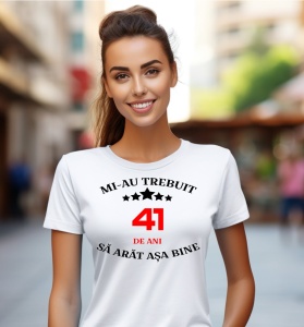 Femeie care poartă un tricou alb personalizat cu mesajul: ''Mi-au trebuit 41 de ani sa arat asa bine''