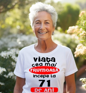 Femeie care poartă un tricou alb personalizat cu mesajul: ''Viata cea mai frumoasa incepe la 71 de ani''.