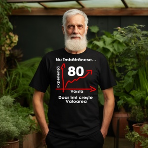 Un bărbat în vârstă, cu barbă albă, purtând un tricou negru cu mesajul: „Nu îmbătrânesc... Doar îmi crește valoarea” și un grafic care indică vârsta de 80 de ani pe axa vârstei și experienței. Bărbatul se află într-un cadru exterior, înconjurat de vegetaț
