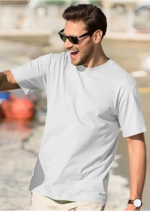 Bărbat purtând ochelari de soare și tricou alb, zâmbind în timp ce stă în aer liber, lângă apă