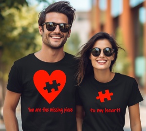 Un bărbat și o femeie purtând tricouri negre cu mesaje romantice. Tricoul bărbatului are un design cu o inimă roșie și o piesă de puzzle lipsă, cu textul 'You are the missing piece', iar tricoul femeii prezintă o piesă de puzzle roșie și textul 'to my hea