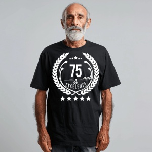 Un bărbat zâmbitor purtând un tricou negru cu textul ''75 de ani de excelență'', înconjurat de o coroană de lauri.