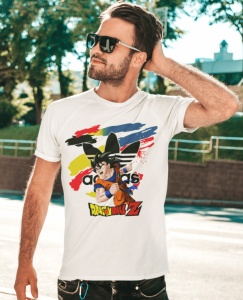 Bărbat purtând ochelari de soare și un tricou alb cu un design colorat ce include un personaj din Dragon Ball Z și un fundal abstract vibrant, pozând într-un cadru exterior, lângă spații verzi.