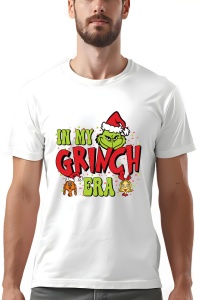 Tricou alb cu design festiv de Crăciun, care prezintă textul 'In My Grinch Era' în culori roșu și verde, alături de un Grinch zâmbitor purtând o căciulă de Moș Crăciun în centrul imaginii. Designul este decorat cu stele și alte două personaje animate în t