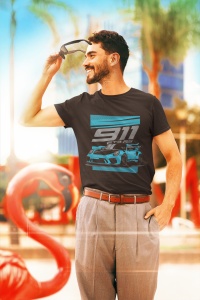 Bărbat zâmbitor purtând un tricou negru cu designul unei mașini sport și textul '911 GT RS', ținând o pereche de ochelari de soare în mână, în fața unui decor tropical cu flamingo decorativ și vegetație în fundal.