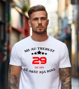 Un bărbat purtând un tricou alb cu mesajul: „Mi-au trebuit 29 de ani să arăt așa bine”