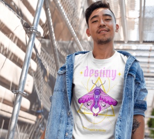 Un tânăr poartă un tricou alb cu un design mistic ce include cuvântul 'destiny' scris cu litere roz și o ilustrație detaliată a unui fluture colorat în nuanțe de mov și roz, în fața unei forme geometrice. Textul de jos spune 'The choice is yours'. Tânărul