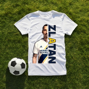 Tricou alb personalizat cu imaginea lui Zlatan Ibrahimović și numele său scris vertical în culori contrastante. Tricoul este așezat pe o suprafață de iarbă verde, având alături o minge de fotbal alb-negru. Contextul sugerează o atmosferă sportivă, ideală 