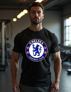 Bărbat purtând un tricou negru cu sigla echipei de fotbal Chelsea FC. Sigla, colorată în albastru și auriu, prezintă un leu albastru ținând un baston, încadrat de un cerc cu inscripția 'Chelsea Football Club' și detalii roșii. Bărbatul se află într-o sală