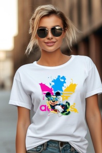Femeie purtând un tricou alb cu un design colorat care prezintă un personaj animat vesel, așezat în fața unui logo adidas stilizat, cu stropi de vopsea vibrantă.
