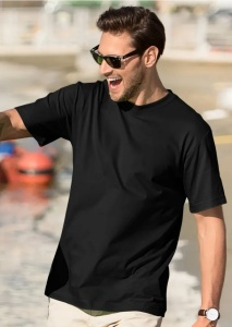 Bărbat purtând ochelari de soare și tricou negru, zâmbind în timp ce stă în aer liber, lângă apă