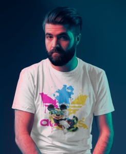 Bărbat cu barbă, purtând un tricou alb cu un design vibrant ce include un personaj animat(Mickey Mouse) și splaturi de culoare roz, albastru și galben, fotografiat într-un cadru cu iluminare artistică în tonuri de albastru și roz.