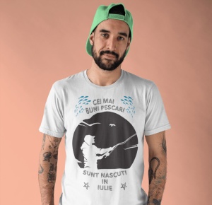 Imagine cu un bărbat purtând un tricou alb pe care este imprimat un design cu mesajul 'Cei mai buni pescari sunt născuți în iulie', cu o siluetă de pescar și ilustrații de pești.