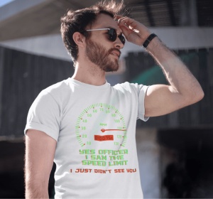 Un bărbat purtând ochelari de soare poartă un tricou alb cu un design ce afișează un vitezometru și mesajul amuzant 'Yes officer, I saw the speed limit, I just didn't see you' în text verde și roșu. Bărbatul își ridică mâna spre frunte, iar fundalul este 