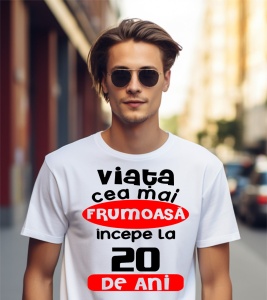 Un bărbat purtând un tricou alb cu textul ''Viața cea mai frumoasă începe la 20 de ani''.