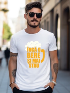 Un bărbat purtând ochelari de soare și un tricou alb cu un design ce include o halbă de bere stilizată și textul în română 'Încă o bere și mai stau'.