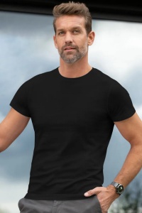 Bărbat purtând tricou negru și ceas la mână, privind spre cameră, în aer liber, cu un fundal parțial înnorat