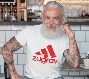 Un bărbat cu barbă albă și tatuaje pe brațe poartă un tricou alb cu un design amuzant inspirat de un logo faimos, înfățișând trei dungi stilizate ca pensule de zugrăvit și textul 'zugrav' scris dedesubt. Bărbatul stă relaxat într-o cafenea.