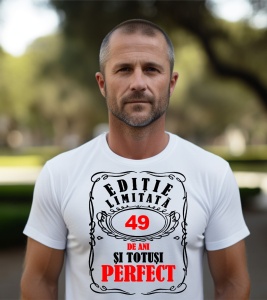 Un bărbat purtând un tricou alb cu mesajul: „Ediție limitată, 49 de ani și totuși perfect”. Bărbatul afișează o atitudine veselă și pozitivă.
