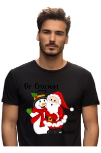Bărbat purtând un tricou negru cu un design de Crăciun, înfățișându-i pe Moș Crăciun și un om de zăpadă îmbrățișându-se, alături de mesajul ‘De Crăciun fii mai bun!’