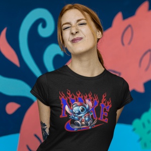 Tânără cu păr roșcat care face o grimasă jucăușă, purtând un tricou negru cu un design grafic colorat(personajul Stitch), pe un fundal vibrant și artistic.