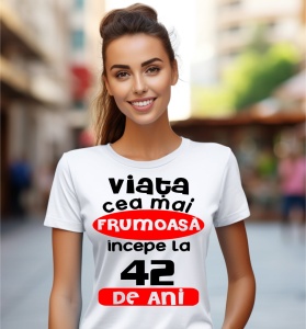 Femeie care poartă un tricou alb personalizat cu mesajul: ''Viata cea mai frumoasa incepe la 42 de ani''.
