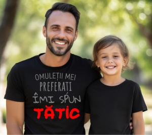 Un tată zâmbitor alături de fiul său, amândoi purtând tricouri negre, tatăl având pe tricou mesajul "Omuleții mei preferați îmi spun TĂTIC", scris cu text gri și roșu, simbolizând legătura lor specială.