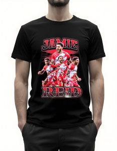 Bărbat purtând un tricou negru cu un design grafic dedicat jucătorului de fotbal Jamie Reid. Grafica include mai multe imagini cu Reid în acțiune, purtând echipamentul echipei sale, într-o combinație de culori roșu și alb. Numele 'Jamie Reid' este inscrip