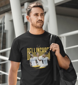 Un bărbat poartă un tricou negru cu un design grafic dedicat jucătorului de fotbal Jude Bellingham, incluzând imagini ale acestuia în acțiune și numele său scris cu litere galbene mari. Bărbatul ține o geantă pe umăr.