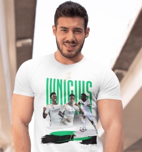 Un bărbat zâmbitor poartă un tricou alb cu un design grafic dedicat jucătorului de fotbal Vinícius, incluzând imagini ale acestuia în acțiune și numele său scris cu litere verzi.