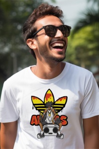 Bărbat cu ochelari de soare zâmbind, purtând un tricou alb cu un design animat ce înfățișează un personaj stil hip-hop, stând pe un casetofon, cu logo-ul Adidas galben și portocaliu pe fundal.