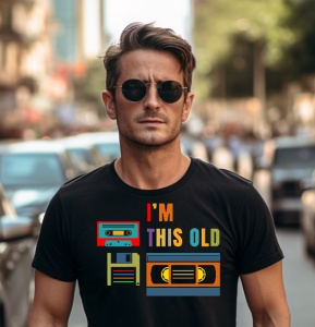 Bărbat purtând ochelari de soare și un tricou negru cu textul 'I'm this old' și desene colorate reprezentând o casetă audio, un floppy disk și o casetă video VHS.