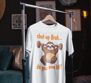 Tricou alb cu un design amuzant ce înfățișează un leneș ridicând greutăți, cu textul 'shut-up Brah... do you even lift?', agățat pe un suport într-o cameră decorată.